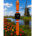 Oranje Holland Apple Watch bandje van BNationX met rood-wit-blauwe details, geïnspireerd op de Nederlandse vlag. Silicone smartwatch band afgebeeld bij typisch Nederlands landschap met molen en tulpenvelden.
