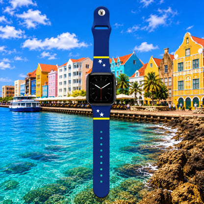 Curaçao Apple Watch horlogebandje van BnationX met blauwe band, gele strepen en witte sterren, afgebeeld voor de kleurrijke kust van Curaçao.