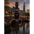 Amsterdam Apple Watch bandje van BNationX met zwarte silicone band, rode strepen en witte Andreaskruizen, geïnspireerd op de Amsterdamse vlag. Smartwatch band afgebeeld bij de Amsterdamse grachten in avondsfeer.