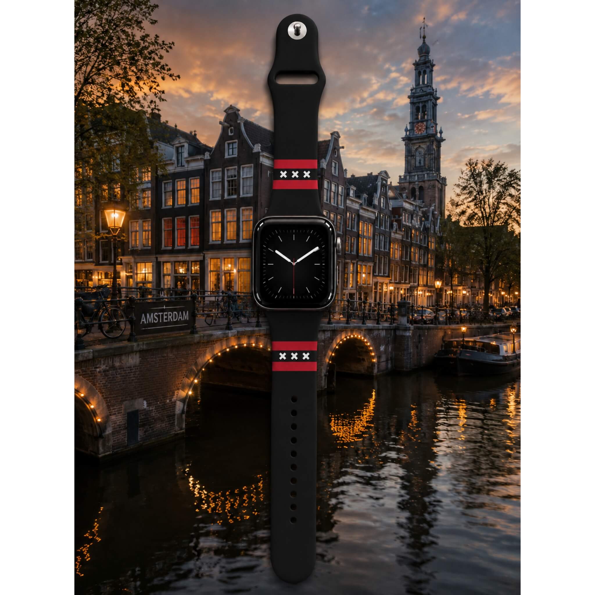 Amsterdam Apple Watch bandje van BNationX met zwarte silicone band, rode strepen en witte Andreaskruizen, geïnspireerd op de Amsterdamse vlag. Smartwatch band afgebeeld bij de Amsterdamse grachten in avondsfeer.