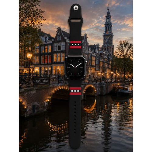 Amsterdam Apple Watch bandje van BNationX met zwarte silicone band, rode strepen en witte Andreaskruizen, geïnspireerd op de Amsterdamse vlag. Smartwatch band afgebeeld bij de Amsterdamse grachten in avondsfeer.