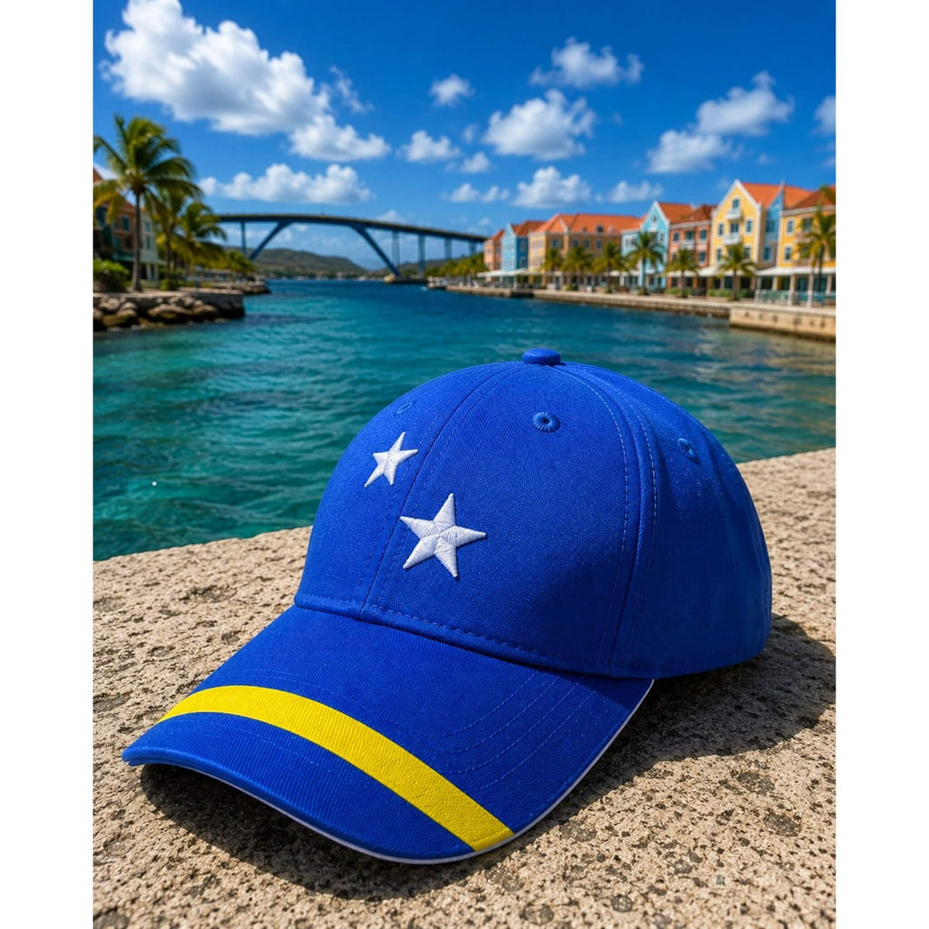 Blauw Curaçao supporterspetje van BNationX met witte sterren en gele streep, geïnspireerd op de Curaçaose vlag. Sportieve cap afgebeeld aan het water van Willemstad Curaçao.