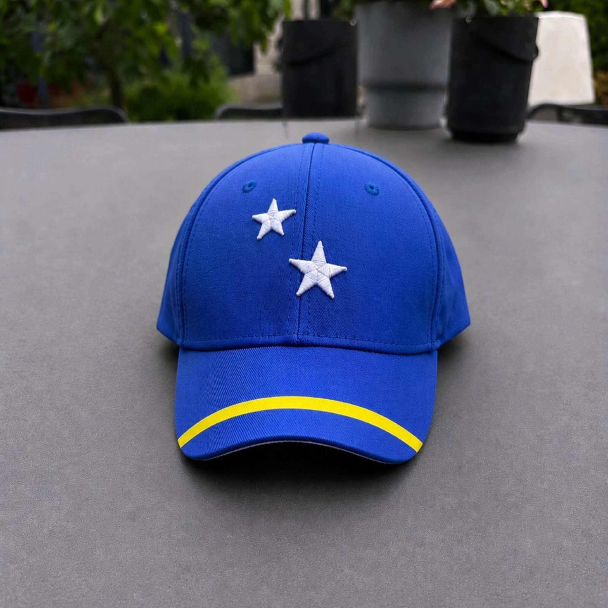 Blauw Curaçao supporterspetje van BNationX met witte sterren en gele streep, geïnspireerd op de vlag van Curaçao. Sportieve cap voor supporters, zomerse outfits en WK voetbal fans.