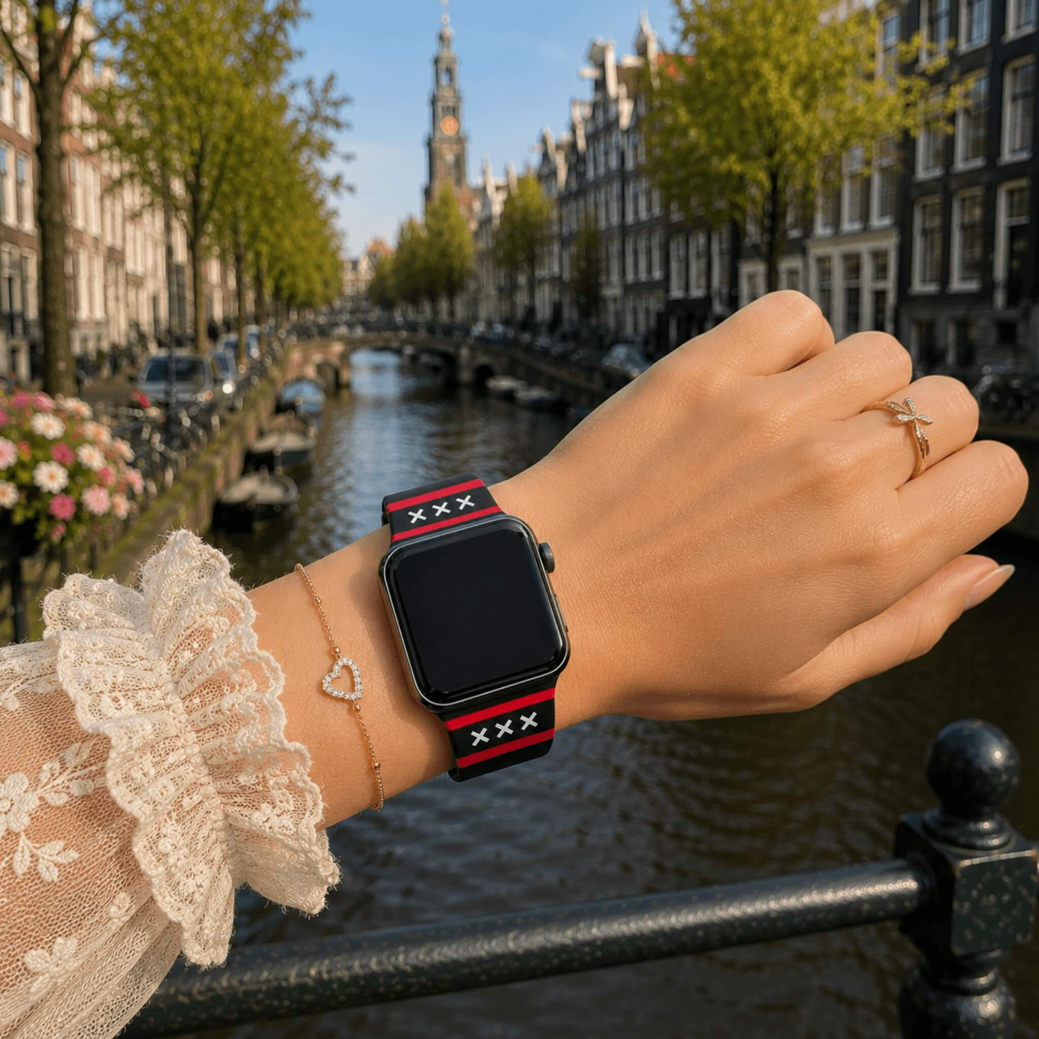 Amsterdam Apple Watch bandje van BNationX met zwarte silicone band, rode strepen en witte Andreaskruizen, gedragen aan de Amsterdamse grachten. Stijlvolle smartwatch band geïnspireerd op de vlag van Amsterdam.